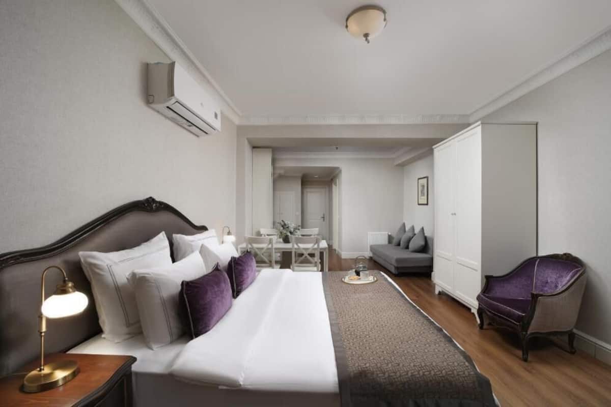 A hotel room with a bed, bedside table, lamp, and a chair.