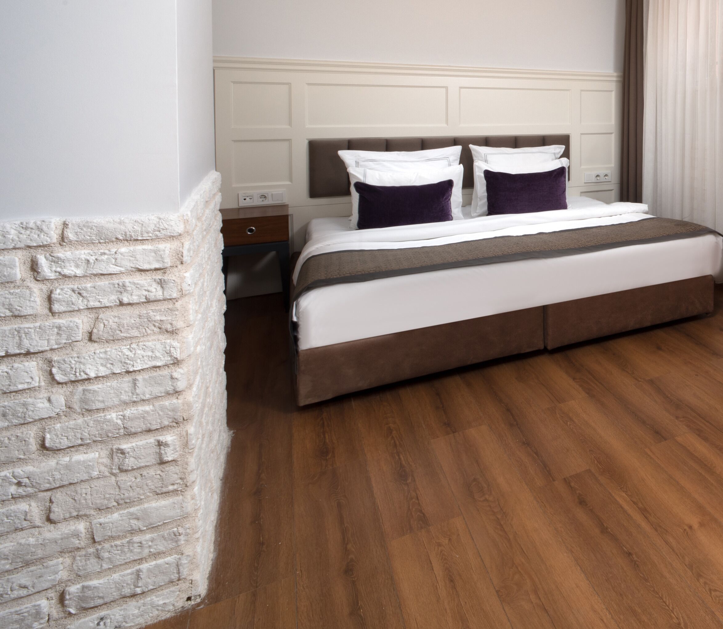Une chambre d’hôtel avec un grand lit, une table de chevet et un mur décoratif en briques.