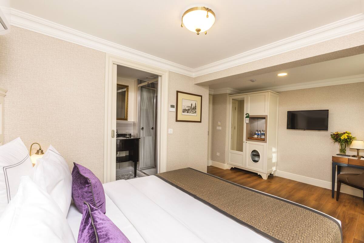 A hotel room with a bed, a desk, a TV, and a bathroom.