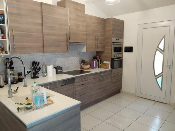 A modern kitchen with wooden cabinets, a built-in oven, and a stainless steel sink.