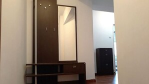 Un corridoio con un armadio in legno scuro, una panca e un mobile nero.