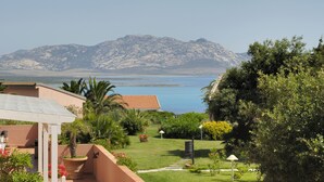 A coastal property with a patio, garden, and mountain view. - Cala Rosa Club Hotel (Stintino)