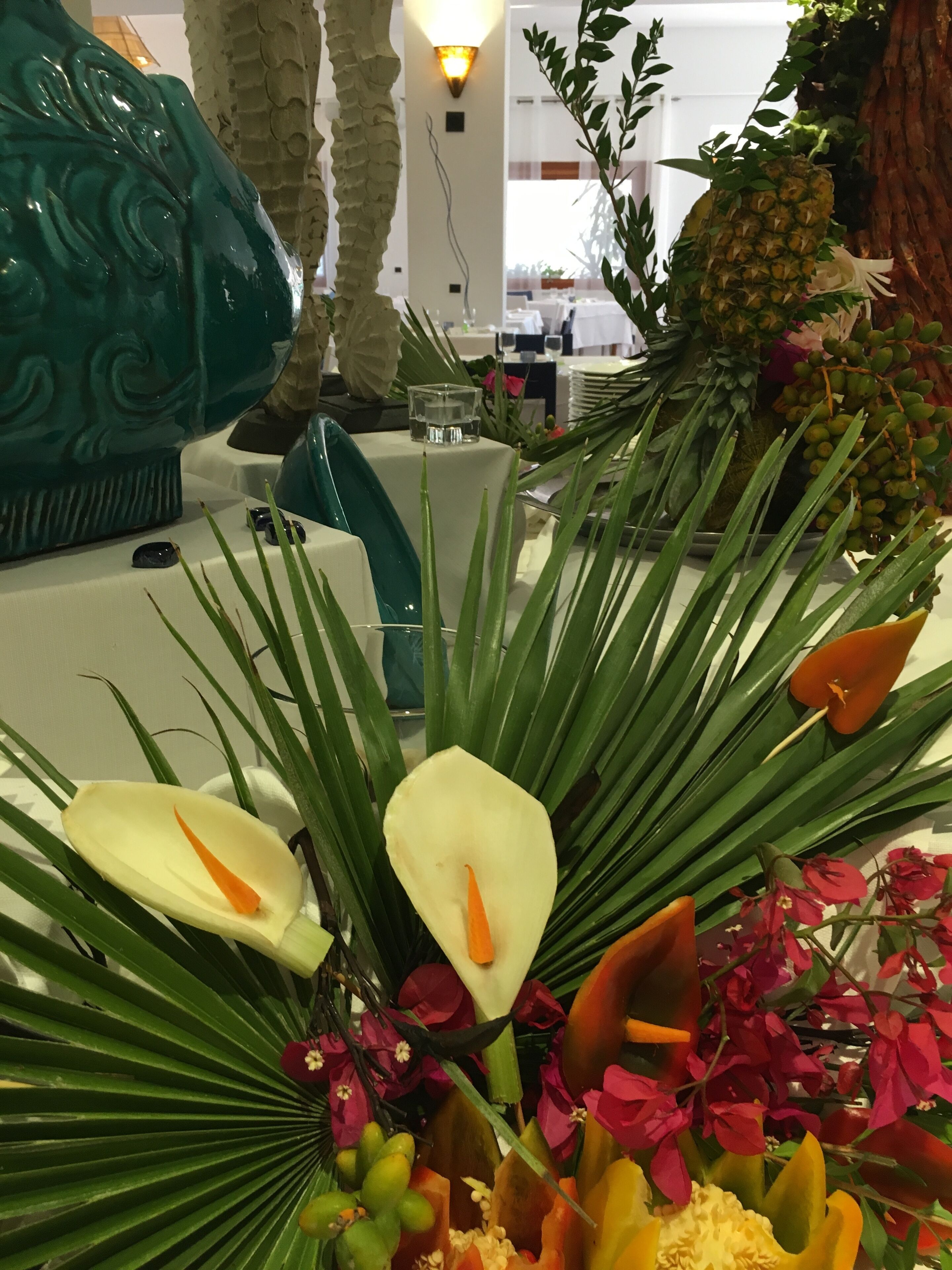Un élément décoratif central composé de plantes tropicales et d’un ananas.