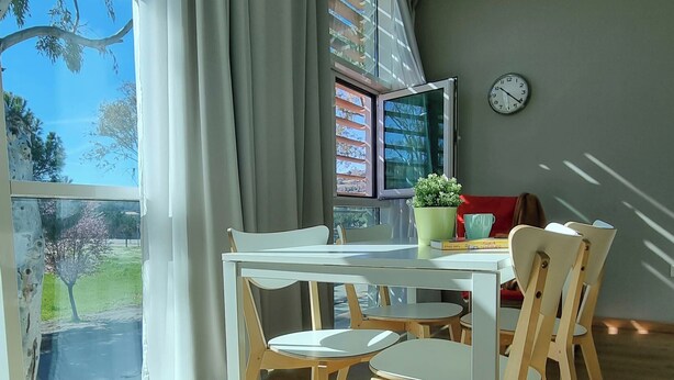 Een eetgedeelte met een tafel, stoelen, een potplant en een klok aan de muur.