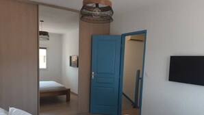 Un dormitorio con cama, armario, espejo y televisión en la pared.