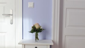 A white console table with a vase of flowers against a light purple wall. - Nice apartment lilac central (Bremen)