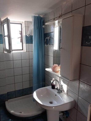 A bathroom with a sink, a mirror, a window, and a shower curtain. - Elegant Apartment (Athens)