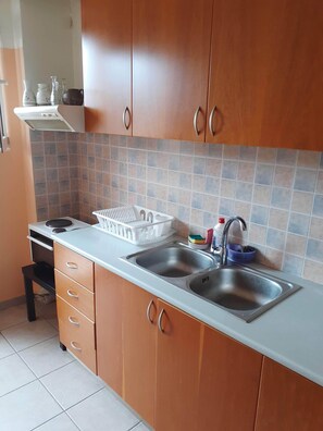 A kitchen with wooden cabinets, a double sink, a stove, and a tiled backsplash.