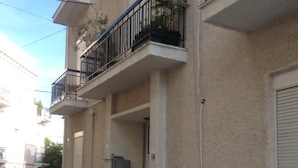A residential building with a balcony, a parked motorcycle, and a car. - Elegant Apartment (Athens)