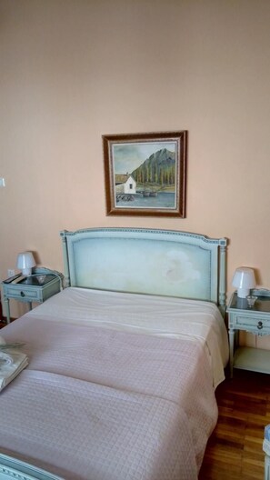 A bedroom with a bed, two bedside tables, a lamp on each table, and a painting on the wall. - Elegant Apartment (Athens)
