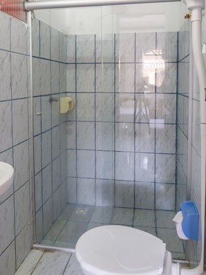 A bathroom with a glass-enclosed shower, a white toilet, and a sink. - Pousada Raysol (Porto Seguro)
