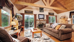 A cozy living room with a fireplace, wooden ceiling beams, and a stone fireplace surround. - Couples, Honeymoon, Anniversary Cabin, convenient to Gatlinburg, National Park (Gatlinburg)