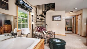A bathroom with a large bathtub, a wooden vanity, a striped armchair, and a staircase. - Couples, Honeymoon, Anniversary Cabin, convenient to Gatlinburg, National Park (Gatlinburg)