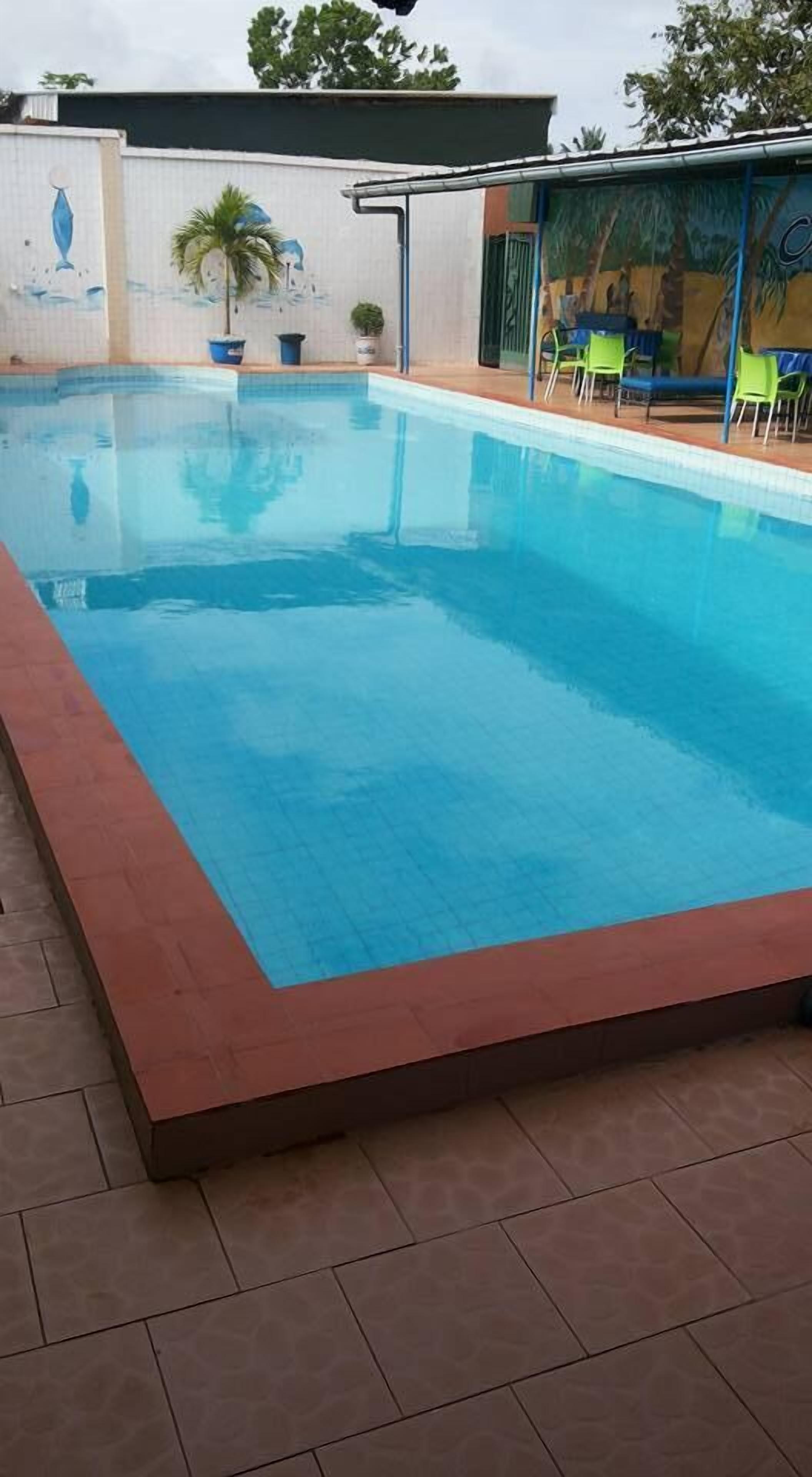 A rectangular swimming pool with a tiled edge, surrounded by a tiled deck.