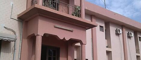 A pink building with a balcony and a sign reading "Hotel Gloria".