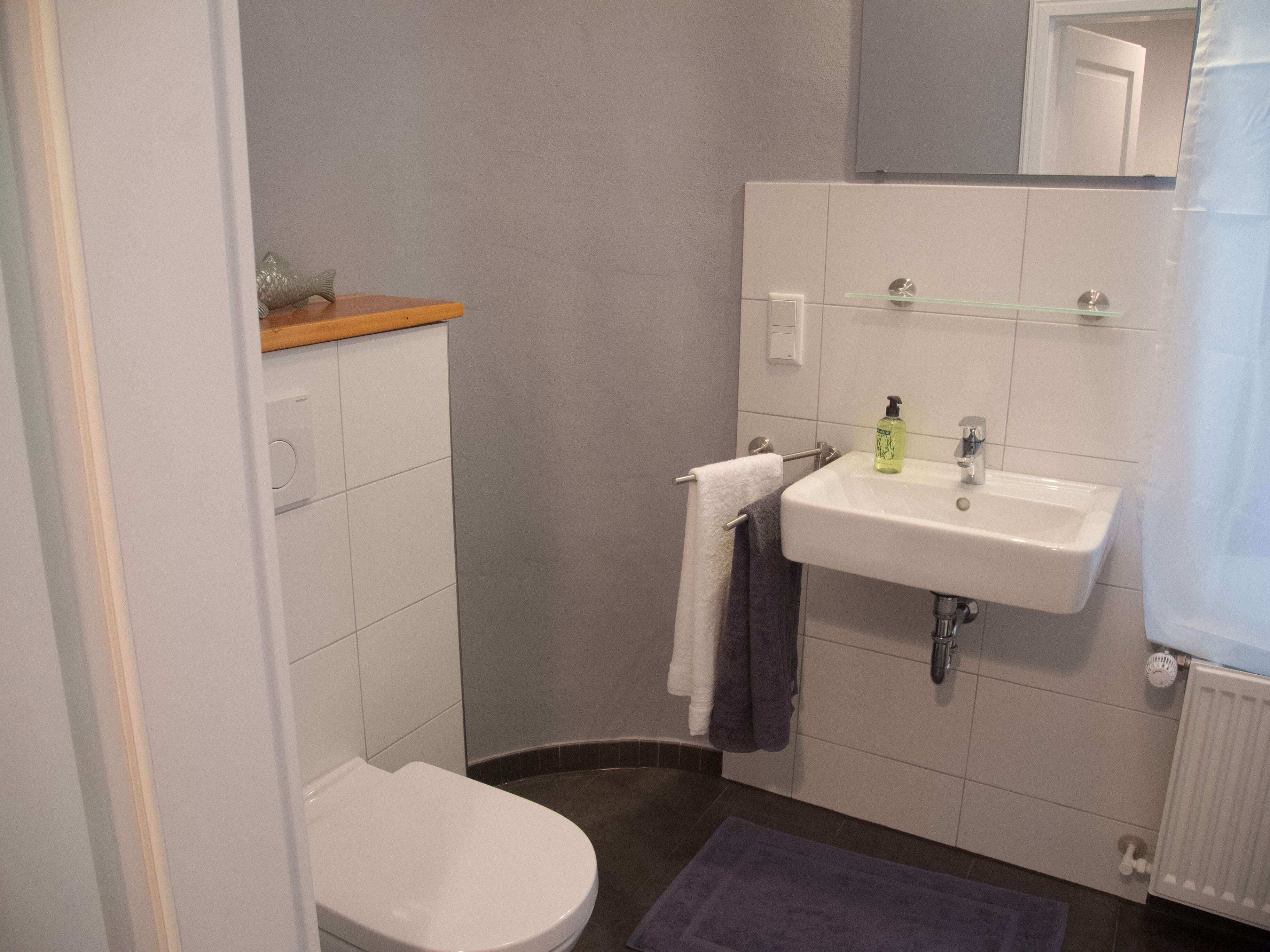 A small bathroom with a toilet, sink, and a mirror.
