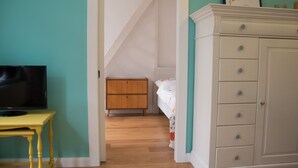 A bedroom with a bed, a dresser, a television on a table, and a staircase leading to an upper room. - Nice apartment turquoise central (Bremen)