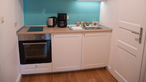 A compact kitchen with a black oven, a coffee maker, and a sink. - Nice apartment turquoise central (Bremen)