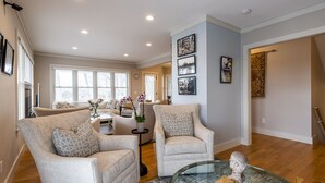A spacious living room with two armchairs, a glass coffee table, and a sofa. There are framed pictures on the wall and a clock on the wall. - Newly Constructed 3 Bedroom, 2 Bath Home on 12.5 Acres, Water Access and Views (WestBrook)