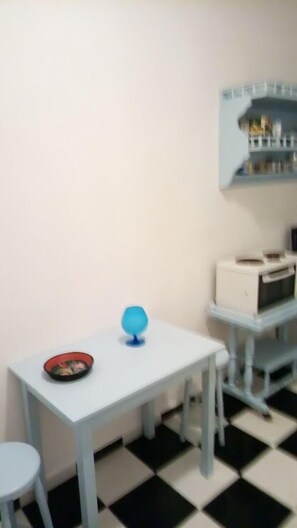A small room with a white table, a blue globe, and a red bowl on the table. There is a black and white checkered floor.