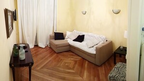 Een woonkamer met een bank, een bijzettafeltje en een poef met zebraprint.