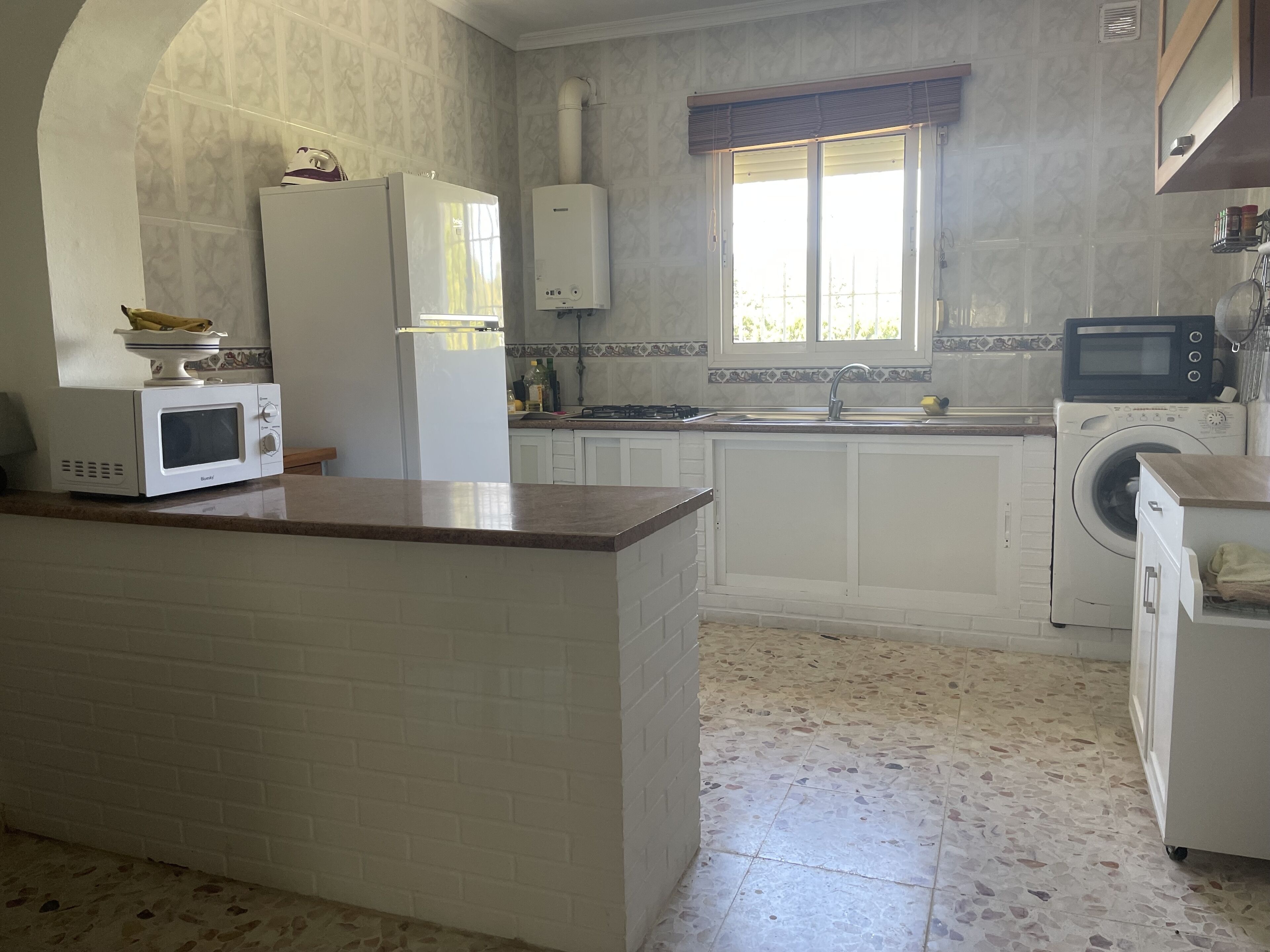 Une cuisine avec un îlot central, un four à micro-ondes, un lave-linge et un évier.