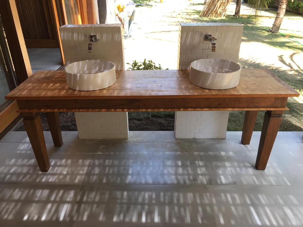 Una panca di legno con due lavabi in ceramica bianca.