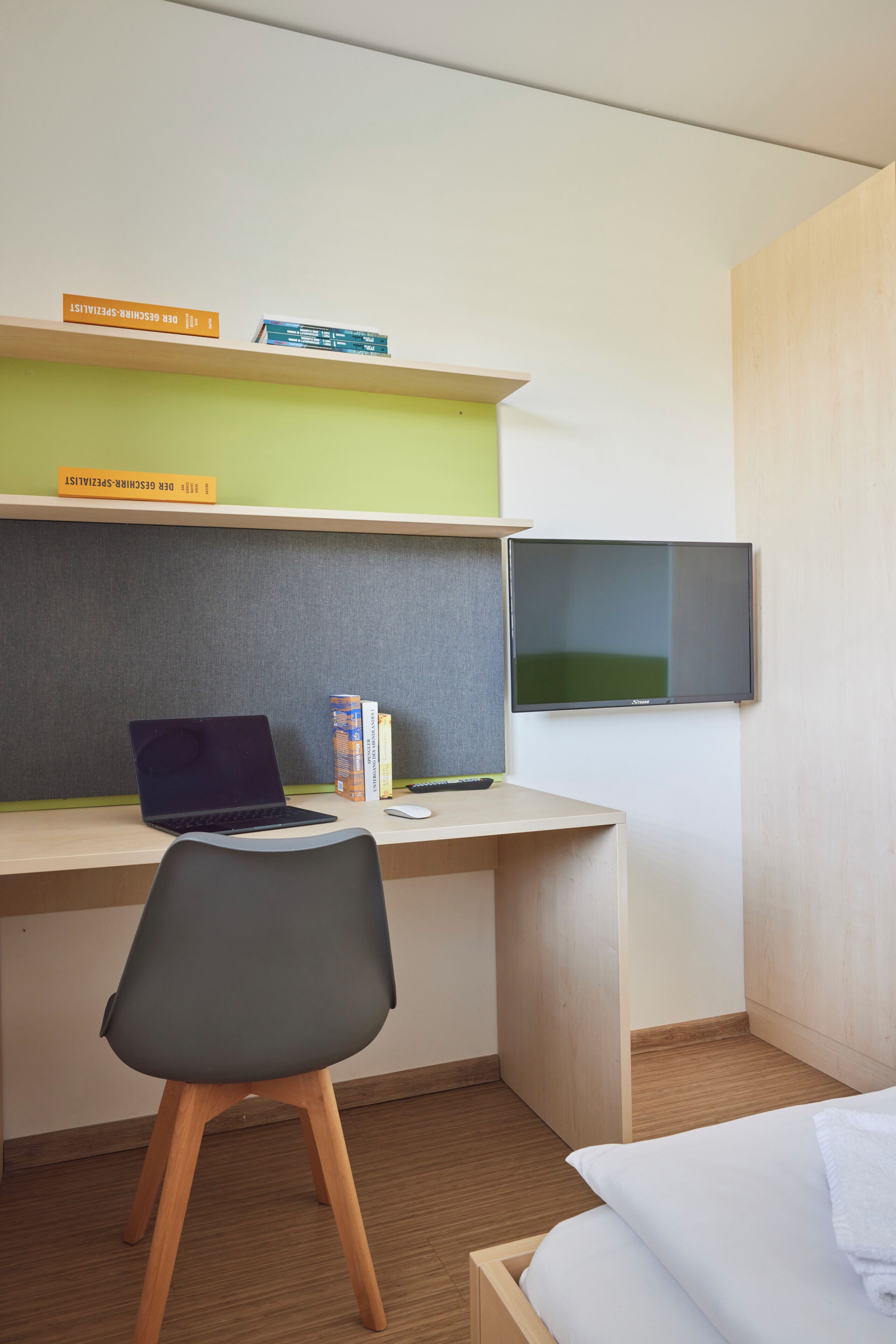 Habitación de hotel con escritorio, silla, cama y televisor.