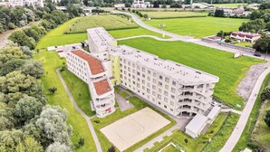 A multi-story hotel with a central courtyard, surrounded by greenery and a sports field. - I AM Hotel Leoben (Leoben)