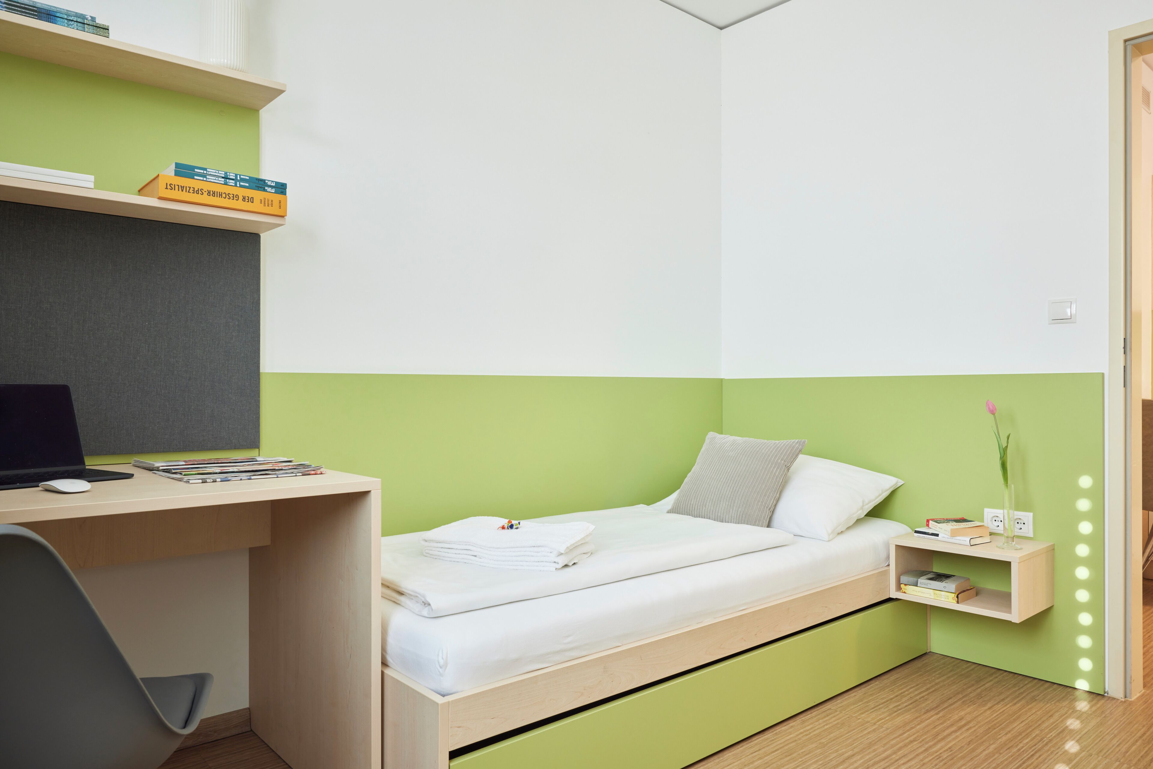 A room with a bed, a desk, a chair, and a nightstand.