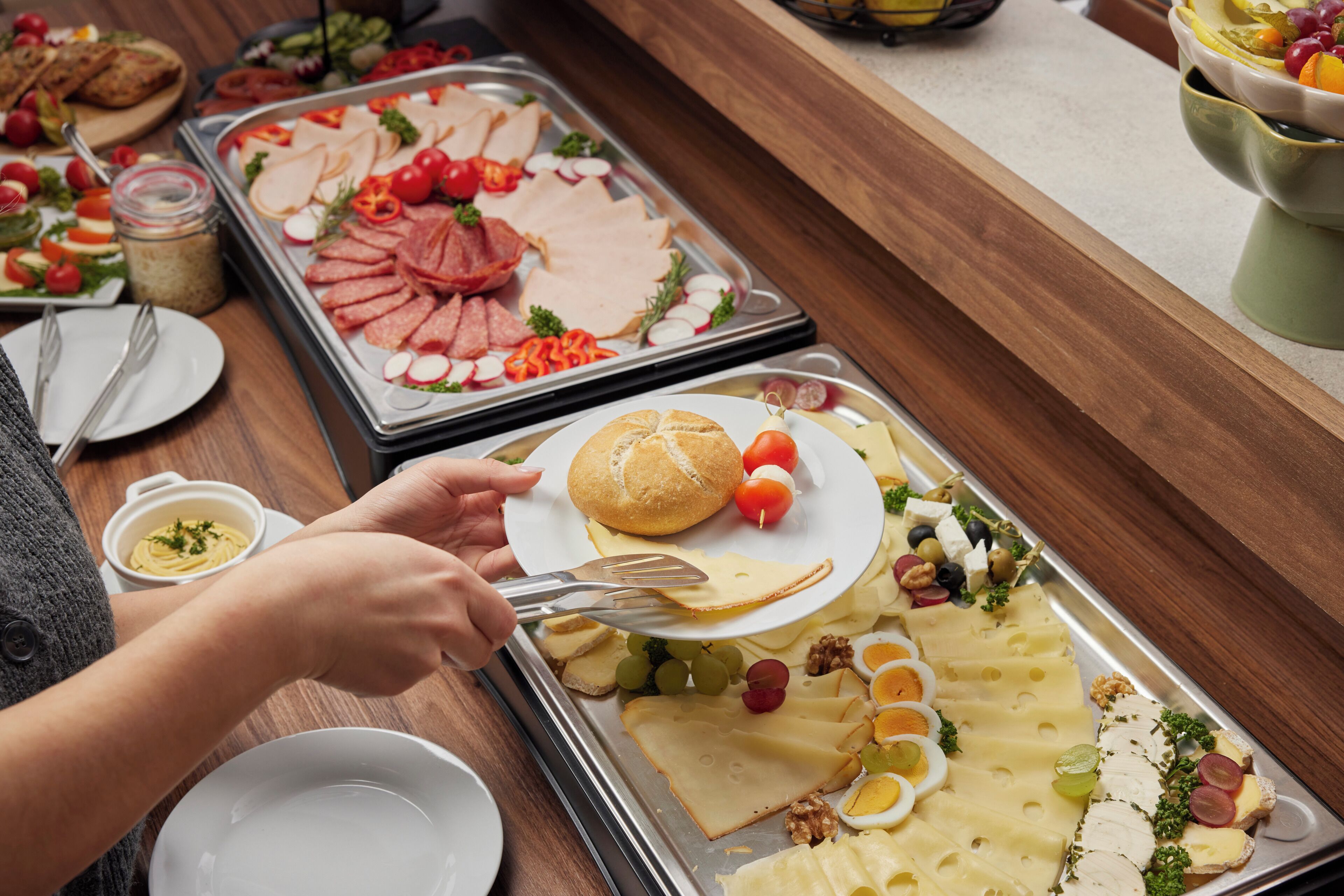 A buffet with various food items including meats, cheeses, and fruits.