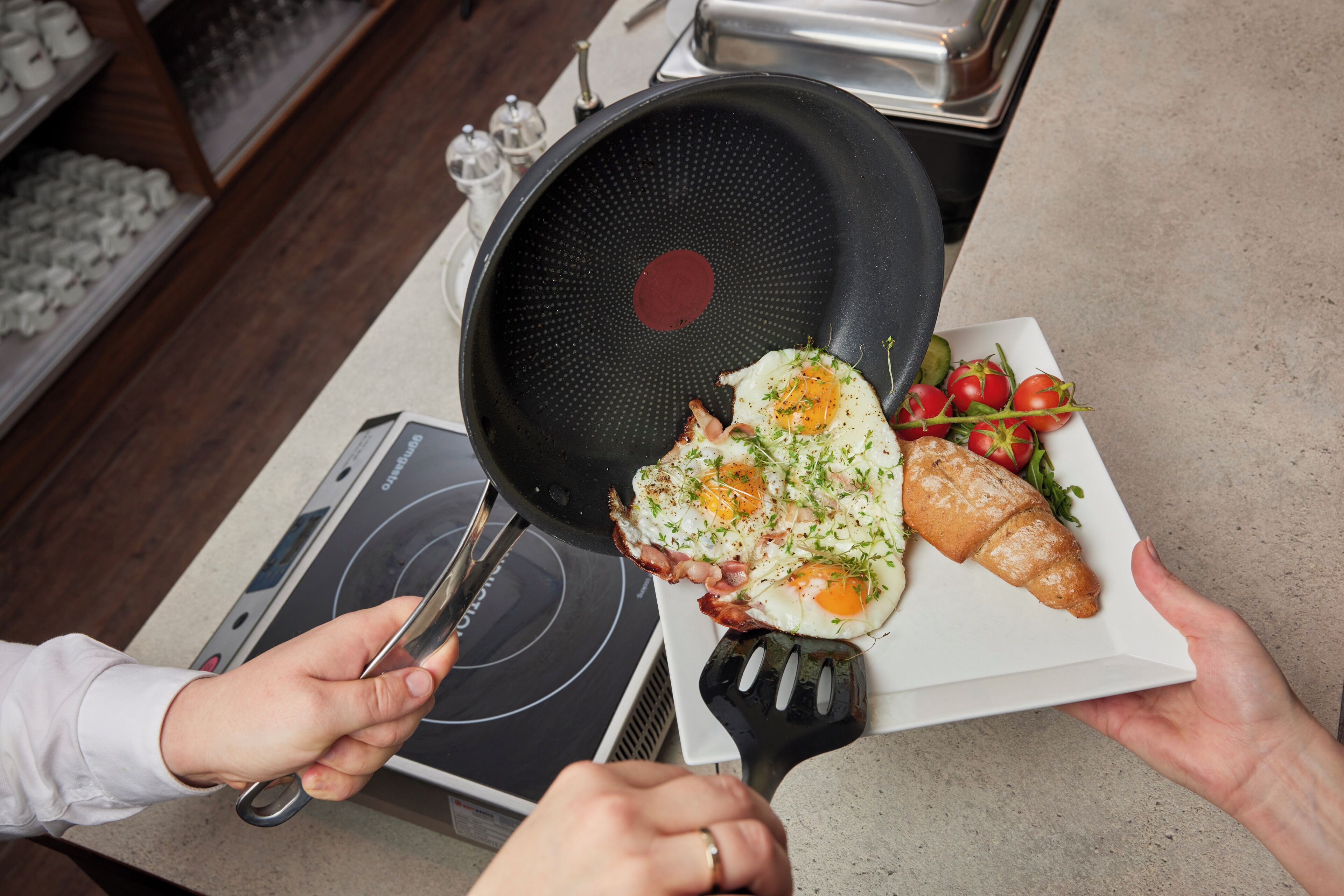 A person cooking an egg in a pan on a stove.