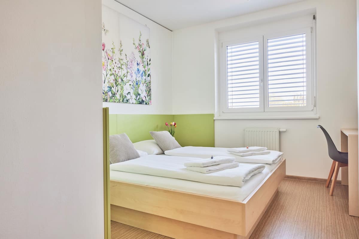 Una habitación con dos camas, un escritorio y una silla.