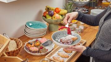A breakfast setting with various pastries, a bowl of fruit, and stacked plates.