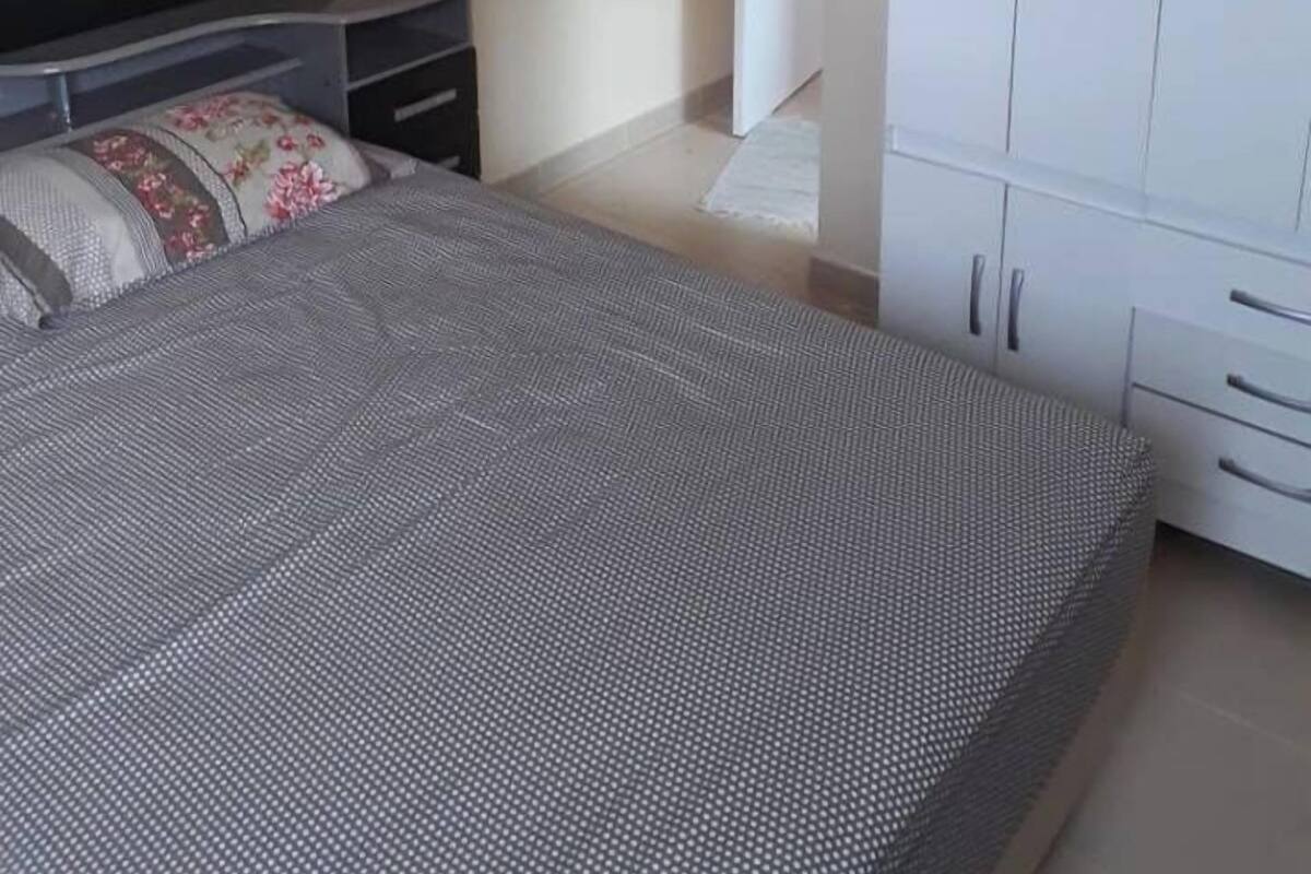 Ein Schlafzimmer mit Bett, Kleiderschrank, Nachttisch und Fernseher.