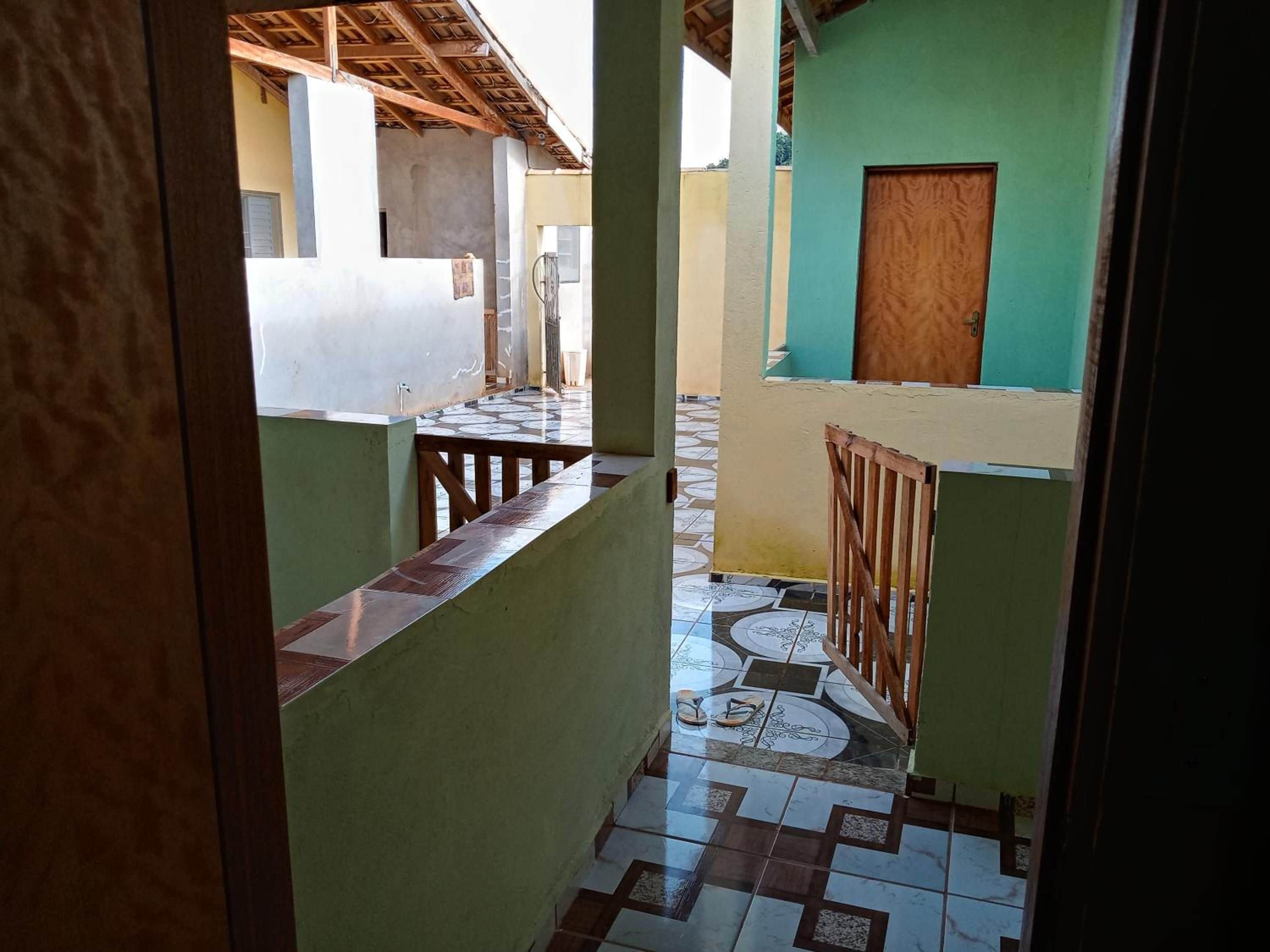 A corridor with a tiled floor, a wooden railing, and a door with a wooden frame.
