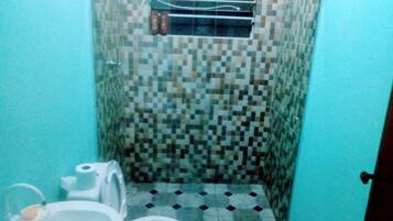 Un baño pequeño con inodoro, lavamanos y zona de ducha.