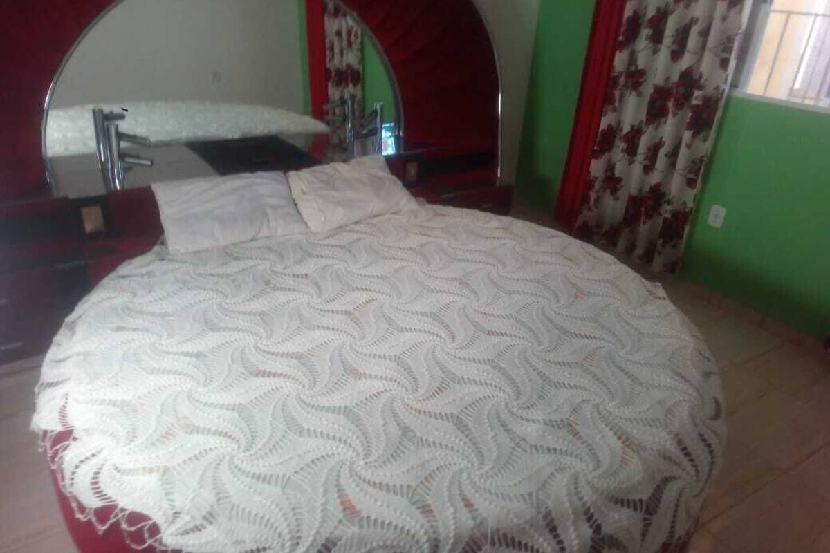 Ein Schlafzimmer mit einem runden Bett, einem großen Spiegel und einem roten Bogen über dem Bett.