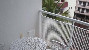 A balcony with a white metal table and chairs, a white railing, and a view of a building with balconies. - Hotel Fazenda Roseira Lagoinha (Ribeirão Preto)