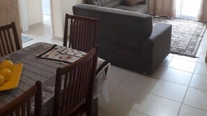 A dining area with a table set for four, a sofa, and a framed picture on the wall. - Hotel Fazenda Roseira Lagoinha (Ribeirão Preto)