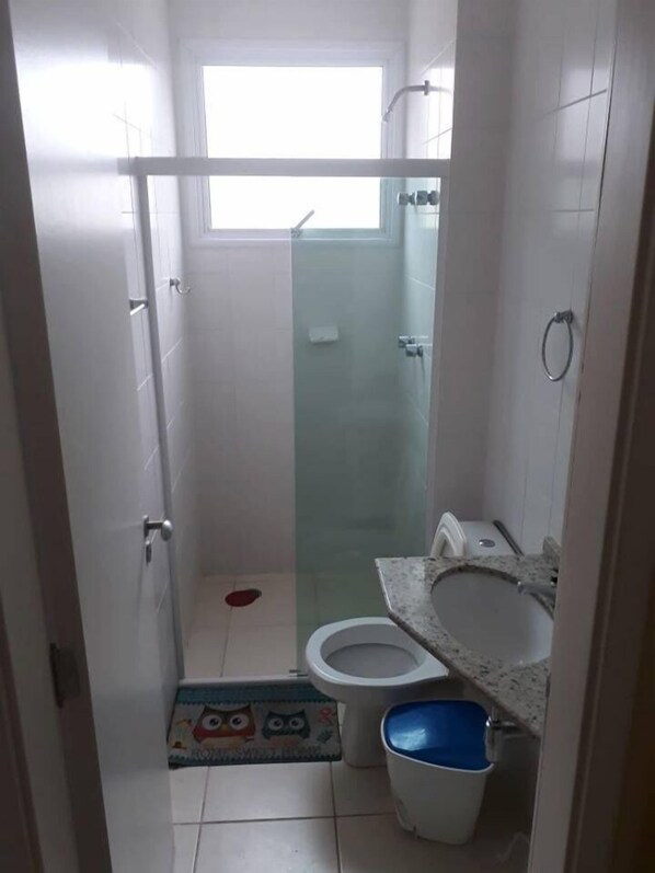 A small bathroom with a toilet, a shower, and a sink.