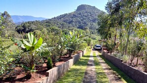 A pathway leading to a building surrounded by lush greenery and a mountain in the background. - Hotel Fazenda Roseira Lagoinha (Ribeirão Preto)
