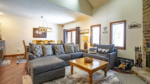 A cozy living room with a sectional sofa, a wooden coffee table, and a fireplace. - Quiet Snow (Davis)