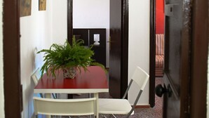 Ein Essbereich mit einem roten Tisch, weißen Stühlen und einem Blumentopf.