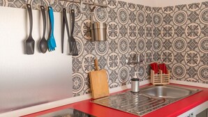 Eine Küche mit roter Arbeitsplatte, einem Edelstahlspülbecken und einer gefliesten Spritzschutzwand.