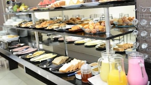 A buffet with various food items and beverages. - Hotel Querência (Pitanga)
