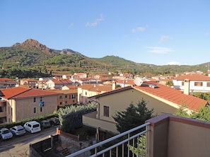 A residential area with red-tiled roofs, a mountain in the background, and a clear sky.