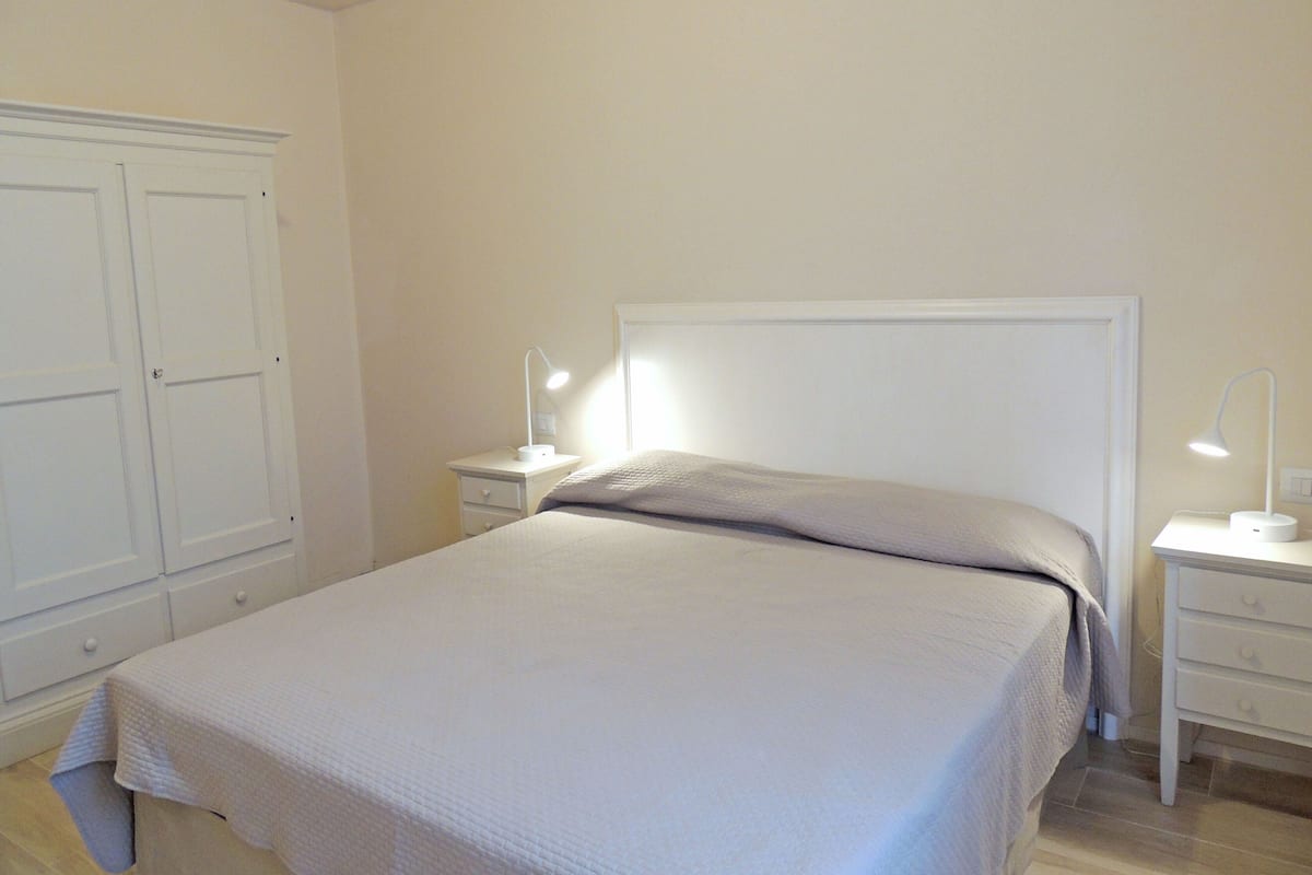 A bedroom with a bed, nightstands, and a wardrobe.
