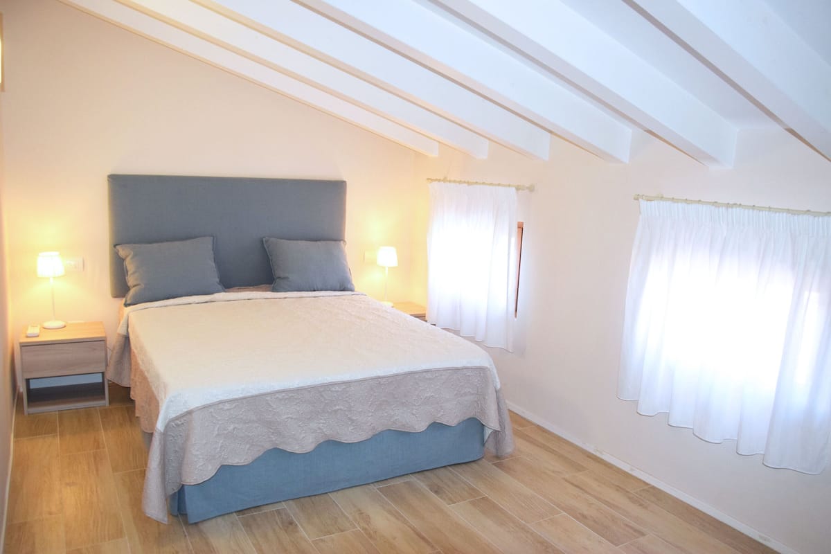 A bedroom with a bed, two bedside tables, and a window with curtains.