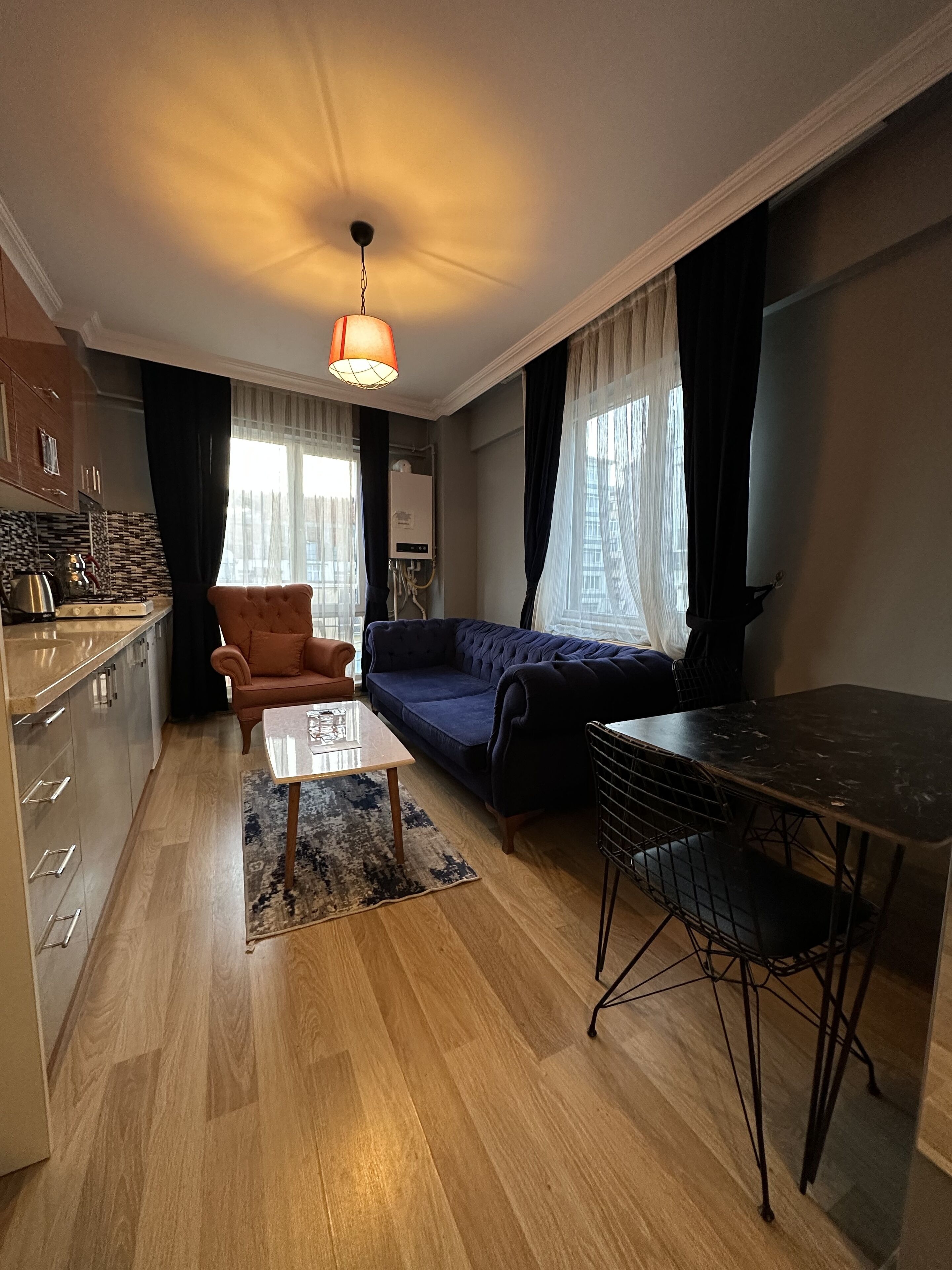 Un espacio habitable compacto con kitchenette, sofá, mesa de comedor y una silla.